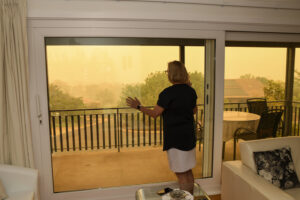 a woman looks out at haze from wildfire